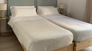 A double bed with a light blue headboard and a geometric patterned bedspread. There are two bedside tables with lamps, a wooden floor, and a hanging light fixture. - Terraza Catedral Olehousing 6 (Sevilla)