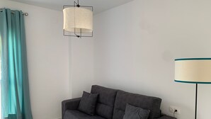 A modern living room with a grey sofa, teal curtains, and a hanging light fixture. - Terraza Catedral Olehousing 6 (Sevilla)