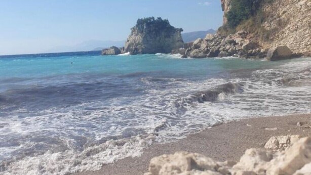 Una spiaggia con acque cristalline color turchese, formazioni rocciose e un litorale sabbioso.