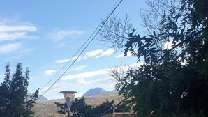 Un edificio con tetto in tegole e finestre ad arco, circondato da alberi e una montagna sullo sfondo.