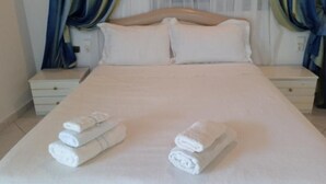 Un letto rifatto con lenzuola bianche e due asciugamani arrotolati.