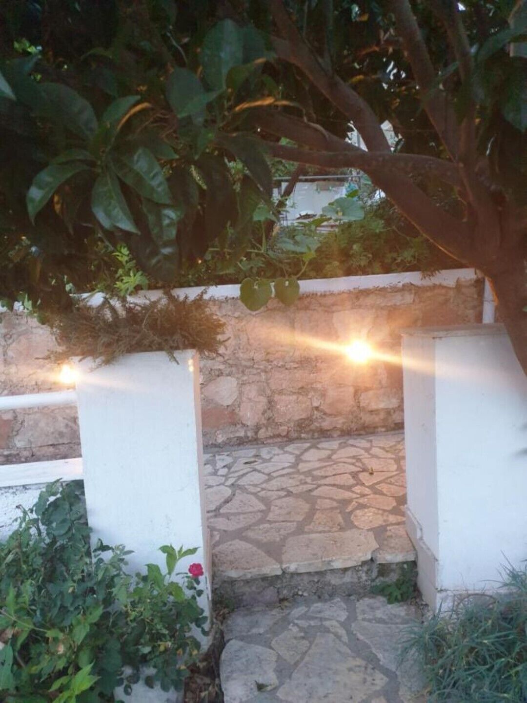 A stone pathway leading to a white wall with a stone floor.