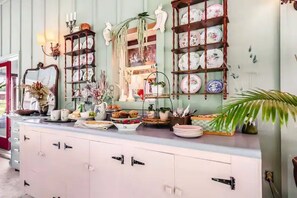 Une cuisine avec un plan de travail blanc, divers plats et objets de décoration.