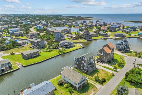 Un quartier résidentiel bordé d’une voie navigable, où se côtoient des maisons individuelles et des immeubles de plusieurs étages, dont certains sont dotés de garages attenants.