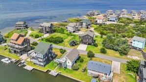 A coastal residential area with houses, a dock, and a view of the sea. - Canalfront Dog Friendly w/ Hot Tub, Boat Dock, Game Room, Nearby Beach Access (Avon)