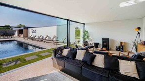 A modern living room with a large glass wall, a pool, and a cozy seating area.