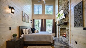 A bedroom with a large bed, a fireplace, and a view of the outdoors.