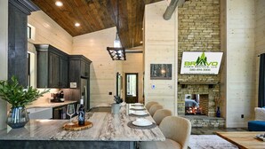 A spacious kitchen with dark wood cabinets, a marble island, and a stone fireplace.