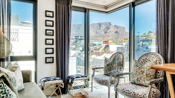 A modern living room with large windows, a sofa, two armchairs, and a coffee table. - Beautiful Apartment with Mountain Views (404 on N) (Cape Town)