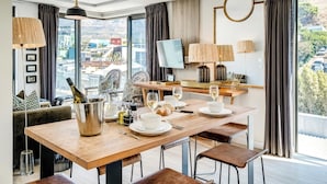 A modern dining area with a wooden table, chairs, and a TV. - Beautiful Apartment with Mountain Views (404 on N) (Cape Town)