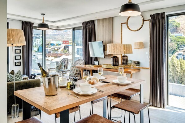 A modern dining area with a wooden table, chairs, and a TV.