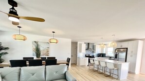 A modern kitchen with white cabinets, a central island with bar stools, and pendant lighting.