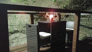 Un área de comedor al aire libre con una mesa y sillas, rodeada por una valla de madera y vegetación.
