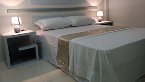 Un dormitorio ordenado con una cama, dos mesitas de noche y un buró.