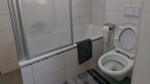 Un baño pequeño y moderno con ducha, inodoro y tragaluz.