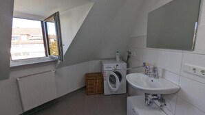 Un baño pequeño y moderno con lavadora incorporada, un lavamanos y un espejo grande.