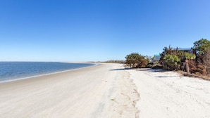 Ein Strand mit blauem Himmel, sandigem Ufer und einem Gebäude mit grüner Dachbegrünung.