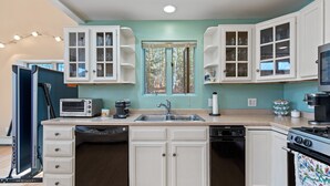 A kitchen with white cabinets, a dishwasher, a stove, and a microwave.