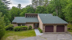 A two-story house with a sloped roof, a front entrance, and a driveway leading to a garage.