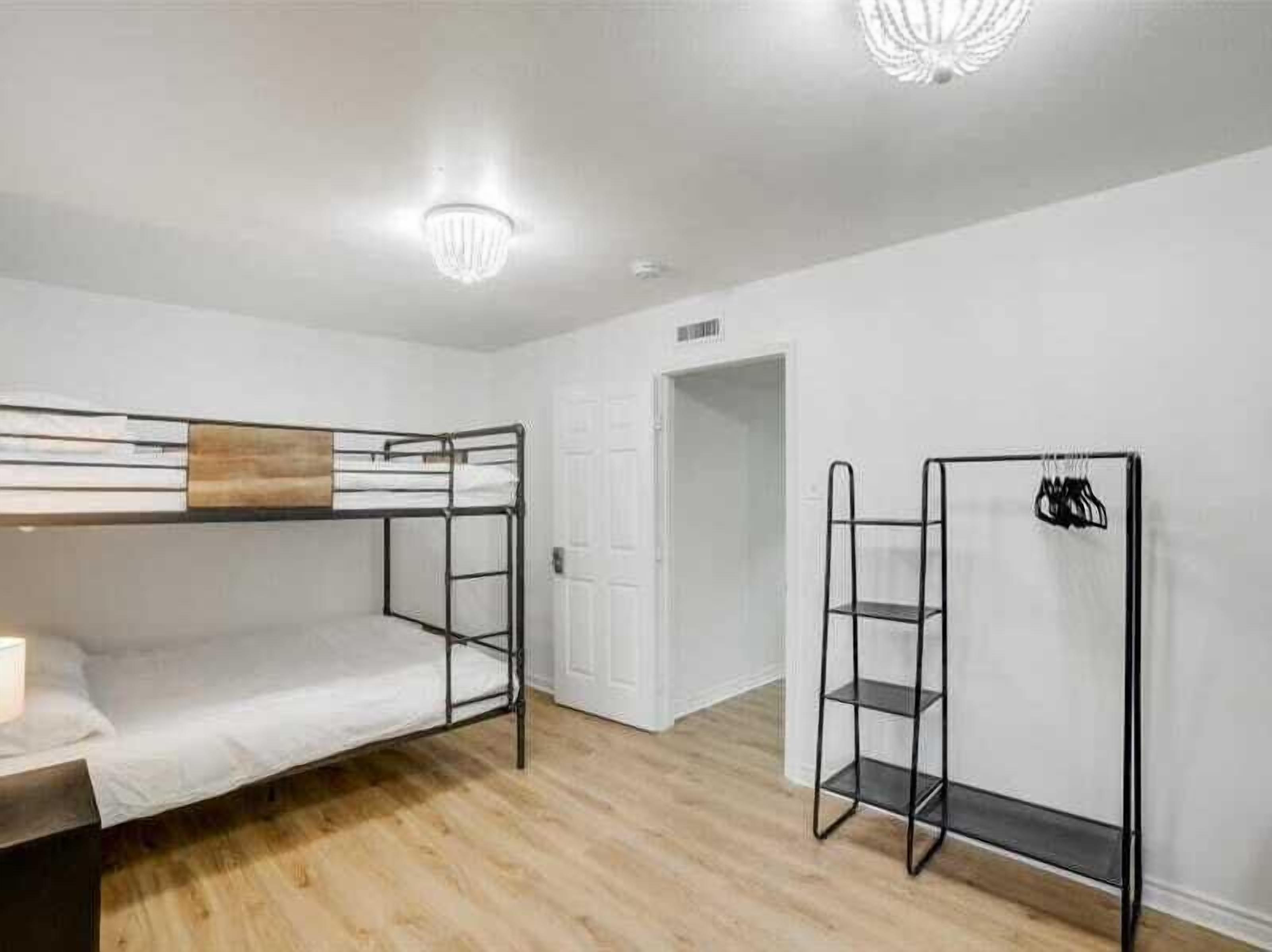 A bunk bed room with a wooden headboard, a metal shelf unit, and a white door.