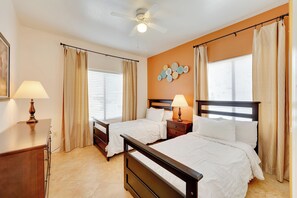 Une chambre d’hôtel avec deux lits, un ventilateur de plafond et une lampe fixée au mur.