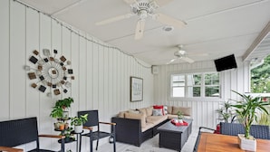 A room with a ceiling fan, a wall-mounted clock, a sofa, and a coffee table. - Destined for Relaxation (Saugatuck)