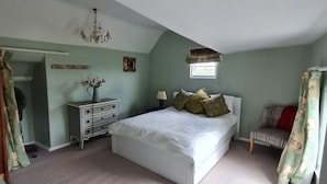 Une chambre à coucher avec un grand lit, une commode, une table de chevet, un lustre et une fenêtre.