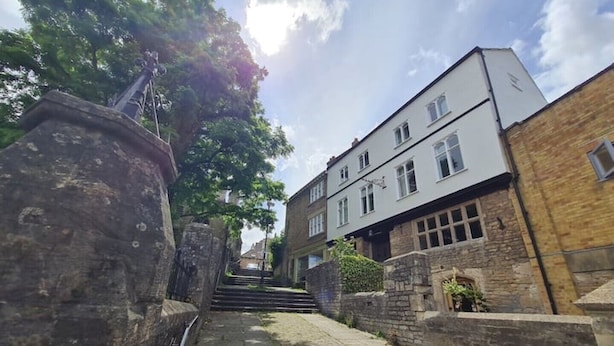 Un escalier en pierre mène à un bâtiment doté de nombreuses fenêtres et d’un mur de briques sur le côté droit.