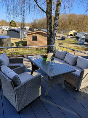 Eine Terrasse mit Korbmöbeln und einem Tisch, umgeben von einem Metallgeländer.