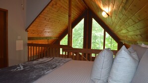 A bedroom with a wooden ceiling, a bed with a gray and white patterned bedspread, and two striped pillows. - Cabin near Fontana and NOC (Bryson City)