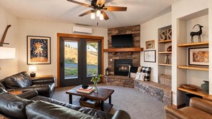 A living room with a fireplace, leather sofa, and a stone wall.