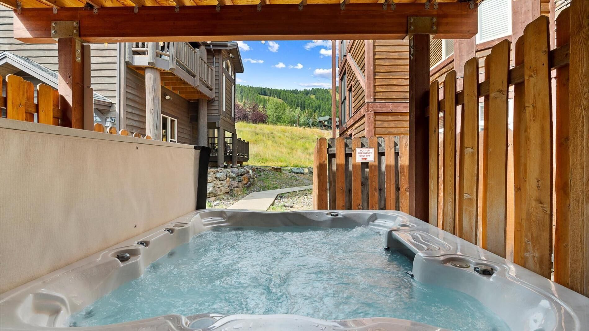 A hot tub area with a wooden deck and a view of a mountain landscape.