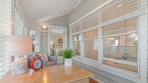 Ein Zimmer mit einem Holztisch, einem roten Wecker, einer weißen Lampe und einem Blumentopf.