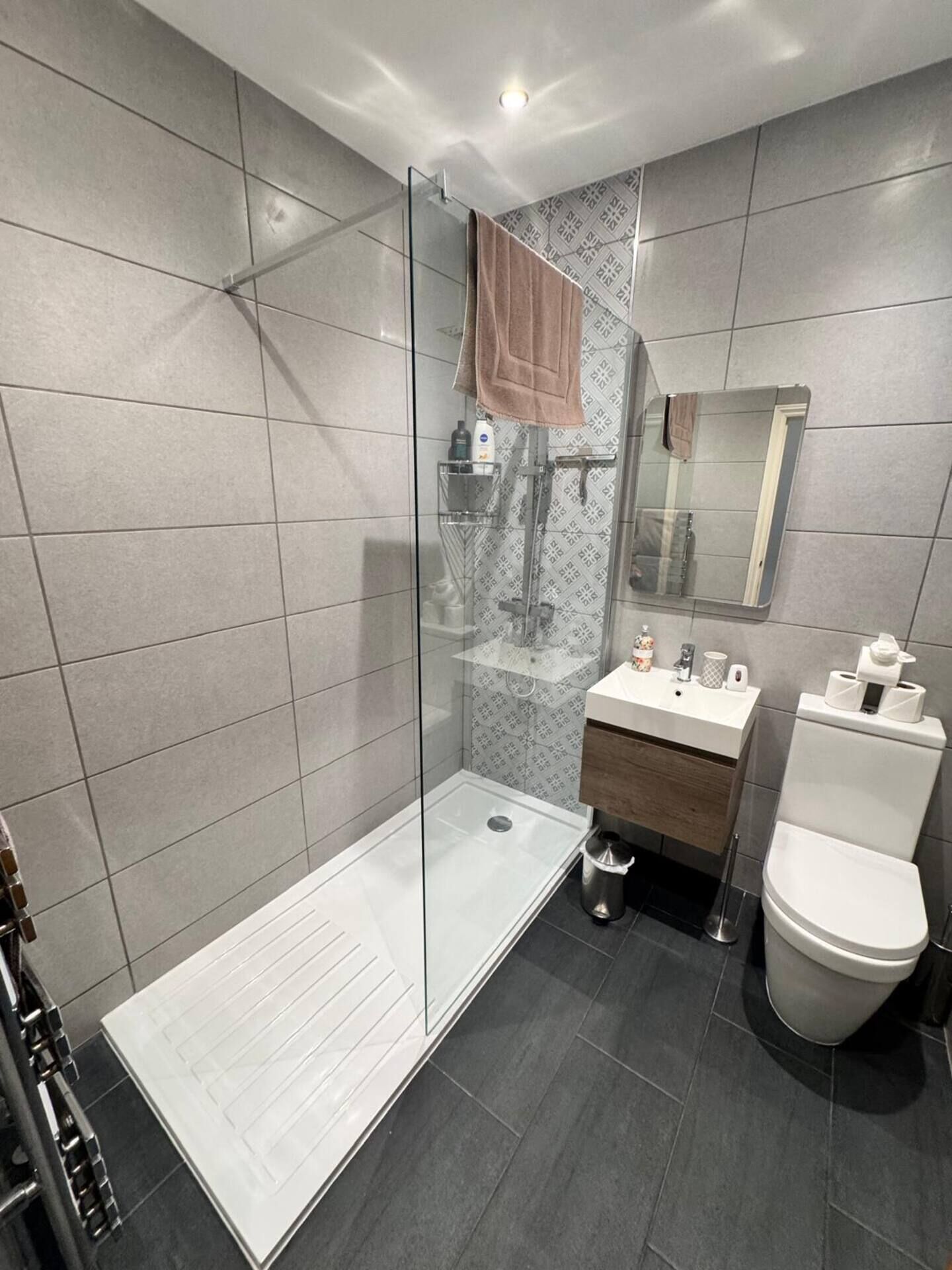 Une salle de bain moderne avec une douche à parois de verre, un lavabo blanc et des toilettes.