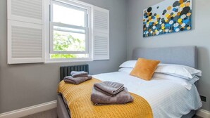 A bedroom with a bed, white bedding, a yellow throw blanket, and a painting on the wall. - Serenity by the Sea - Broadstairs (Kent)