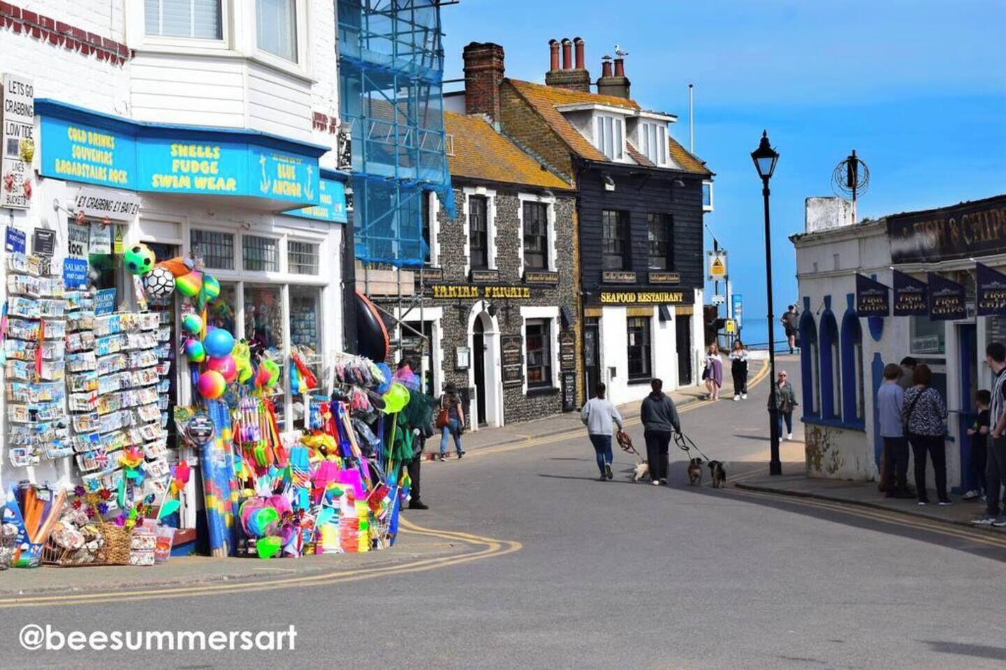 A street with shops, including a seafood restaurant and a store with colorful items.