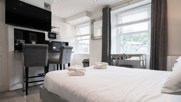 Una habitación de hotel moderna con una cama, un escritorio, una silla, un televisor y una ventana con cortinas.