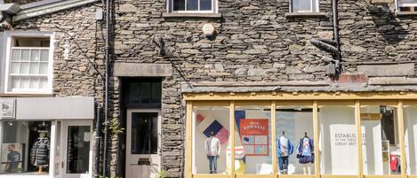 A stone building with a storefront featuring mannequins and a sign that reads "HELLO BOWNESS".