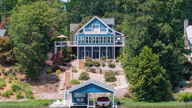 A large house with a dock and a covered area, surrounded by trees and a lake. - MAIN LAKE VIEWS - Fire Pit - Kayaks, SUPs - Pool Table - Bikes (Littleton)