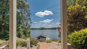 A pathway leading to a dock over a lake, surrounded by trees and a small building. - MAIN LAKE VIEWS - Fire Pit - Kayaks, SUPs - Pool Table - Bikes (Littleton)