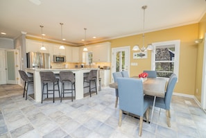A modern kitchen with white cabinets, stainless steel appliances, and a central island with bar stools.