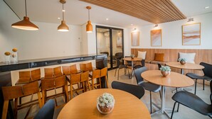 A modern hotel lobby with wooden furniture, pendant lighting, and artwork on the walls.