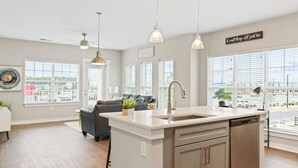 A modern kitchen with a central island, pendant lights, and a view of the city through large windows.