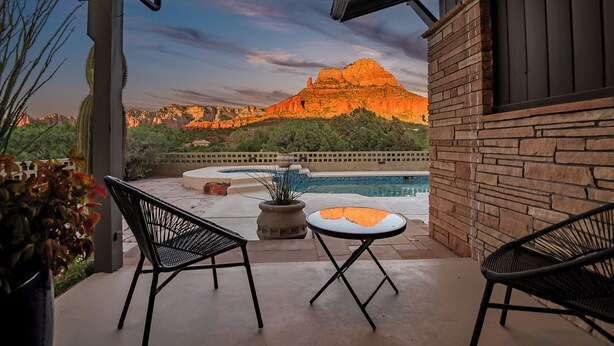 Une terrasse avec deux chaises, une petite table et une piscine.