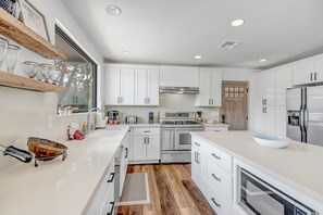 Enjoy cooking in this kitchen with a stainless steel range, oven, and large island with a bowl.