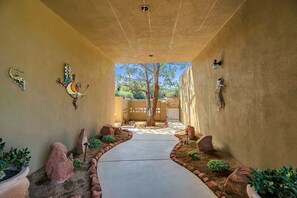 Stroll through the corridor lined with vibrant artwork, leading to a serene gated area with a tree and scenic views.