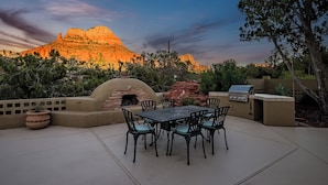 Une terrasse extérieure avec une table et des chaises, un barbecue et un four en pierre.