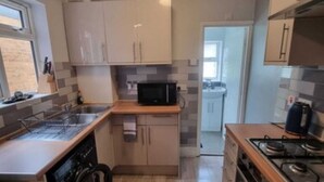 A compact kitchen with a washing machine, microwave, and gas stove. - Orpington RSG House (Orpington)