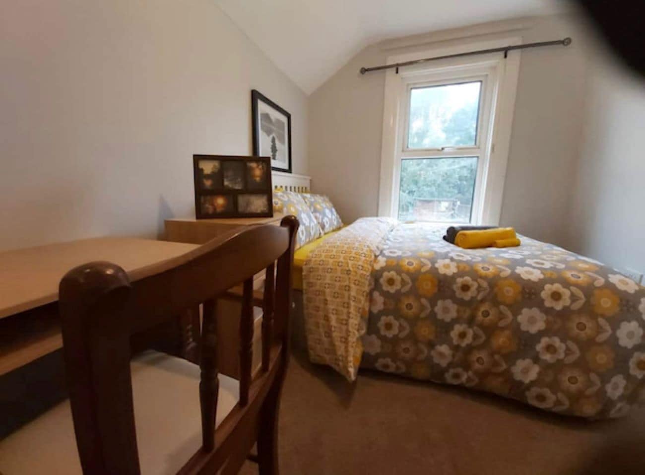 A bedroom with a bed, a chair, a desk, and a window.