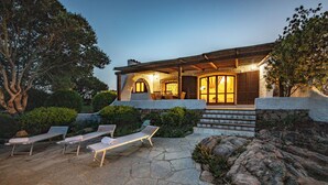 A stone house with a covered patio, outdoor seating, and a warm light. - Villa Isa 6, Emma Villas (Altura)
